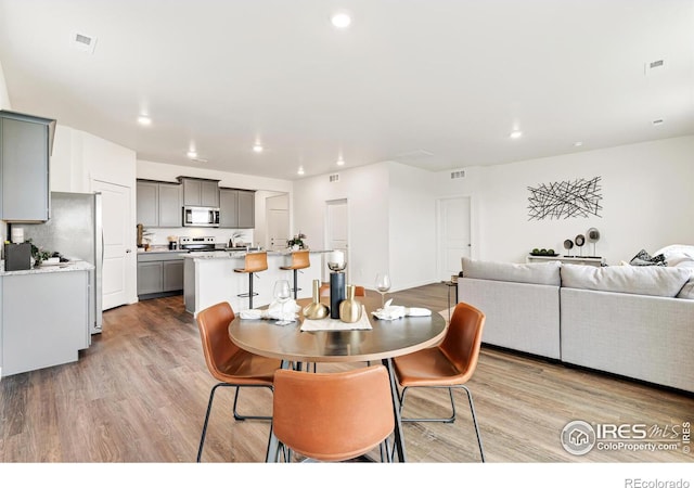 dining space with light wood-type flooring, visible vents, and recessed lighting