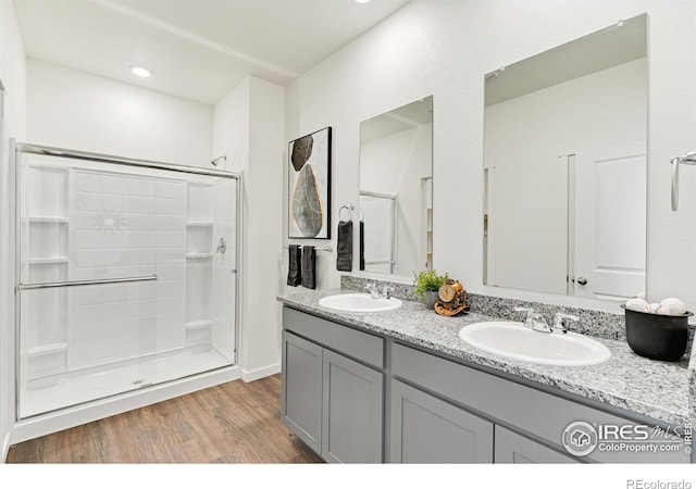 full bath featuring a sink, a shower stall, and wood finished floors