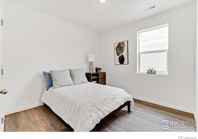 bedroom featuring wood finished floors, visible vents, and baseboards