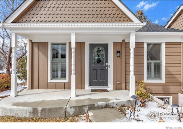 view of exterior entry with board and batten siding and roof with shingles