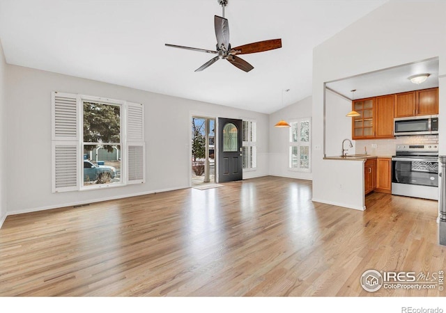 unfurnished living room with light wood-style floors, a ceiling fan, vaulted ceiling, a sink, and baseboards