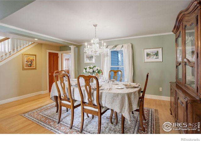 dining space with ornamental molding, light wood finished floors, an inviting chandelier, and baseboards