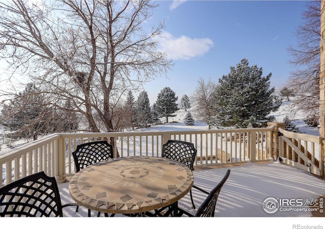 snow covered deck featuring outdoor dining area