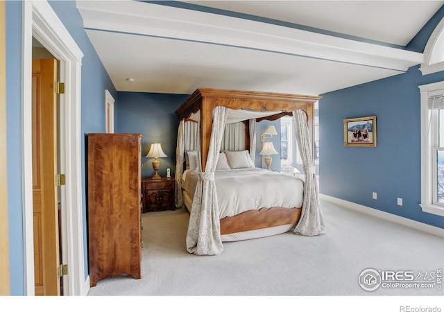 bedroom with light carpet, multiple windows, baseboards, and beamed ceiling