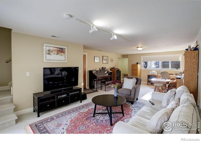 living area featuring visible vents, stairway, light carpet, track lighting, and baseboards