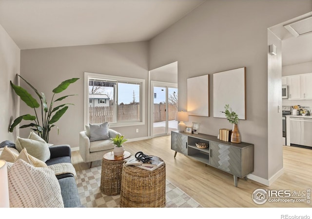 living area featuring vaulted ceiling, light wood finished floors, and baseboards