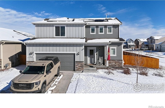 view of front facade with a garage, roof mounted solar panels, and board and batten siding