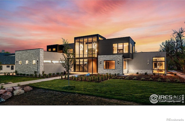 contemporary home with stairs, a yard, and stone siding