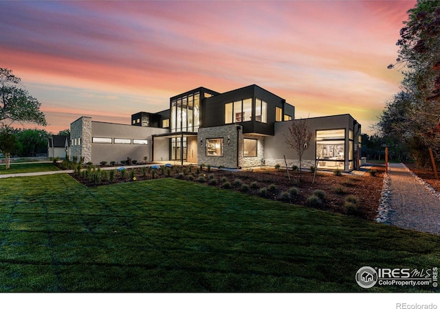 contemporary house featuring stone siding and a front lawn