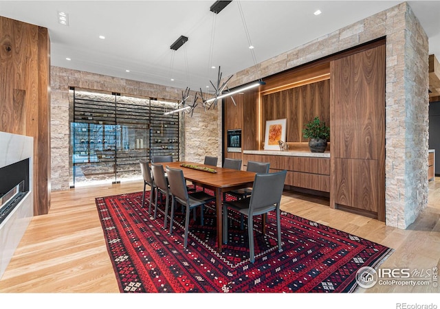 dining area featuring a multi sided fireplace and light wood-style floors