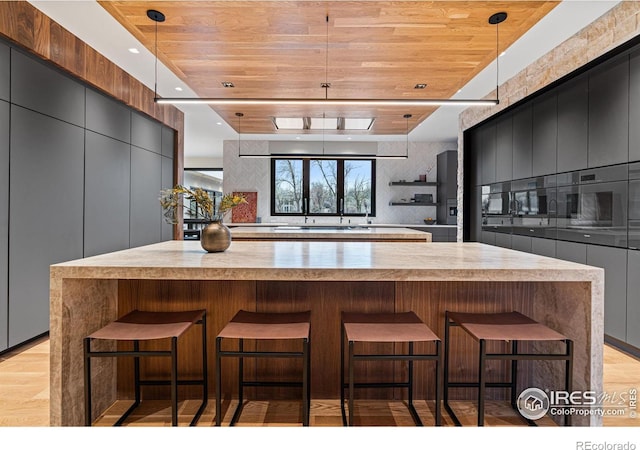 kitchen featuring wooden ceiling, a large island, modern cabinets, and decorative light fixtures