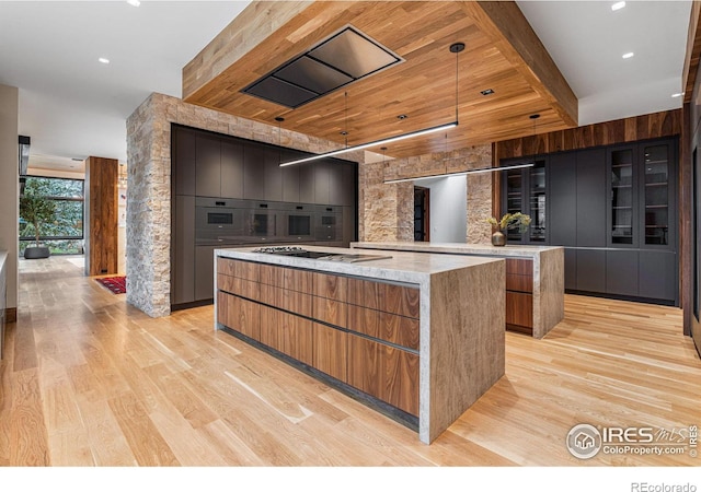 kitchen with a large island, light wood-type flooring, brown cabinets, modern cabinets, and glass insert cabinets