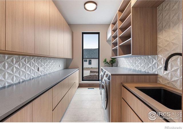 laundry area featuring cabinet space, washer and clothes dryer, a sink, and light tile patterned flooring