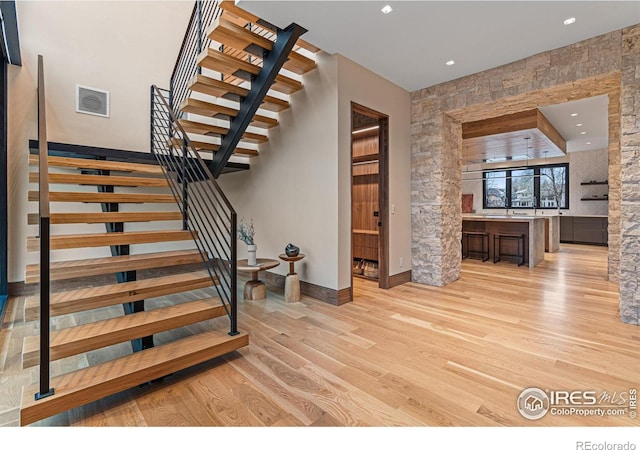 staircase with visible vents and wood finished floors