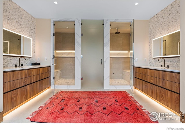 full bath with a shower stall, two vanities, and a sink