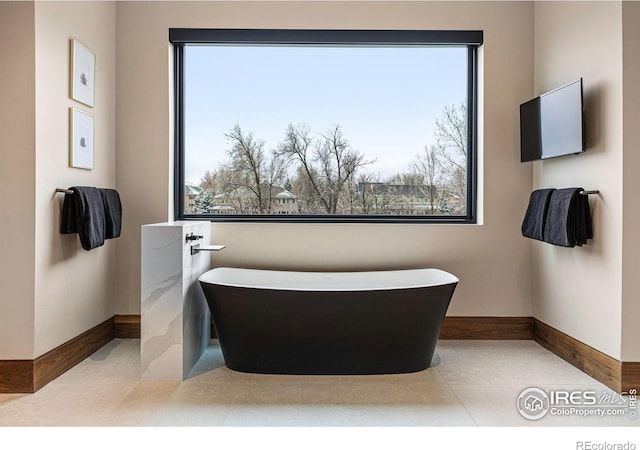 bathroom featuring a freestanding tub and baseboards