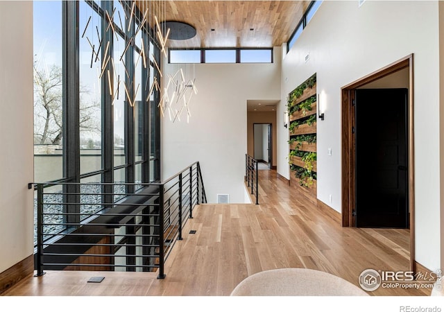 hallway featuring a towering ceiling, an upstairs landing, and wood finished floors