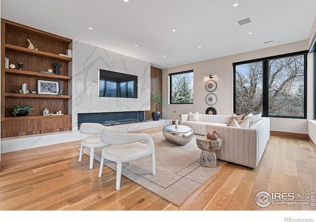 living area featuring light wood-type flooring, visible vents, a fireplace, and recessed lighting