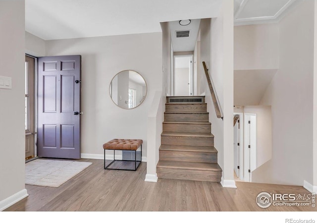 foyer entrance featuring stairway, visible vents, light wood-style flooring, and baseboards