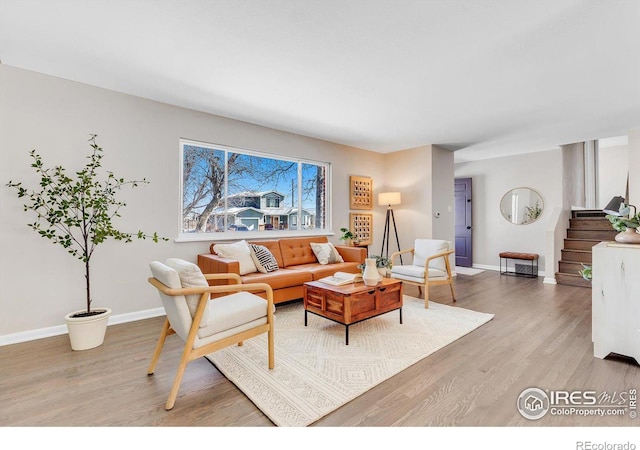 living room featuring baseboards, stairway, and wood finished floors