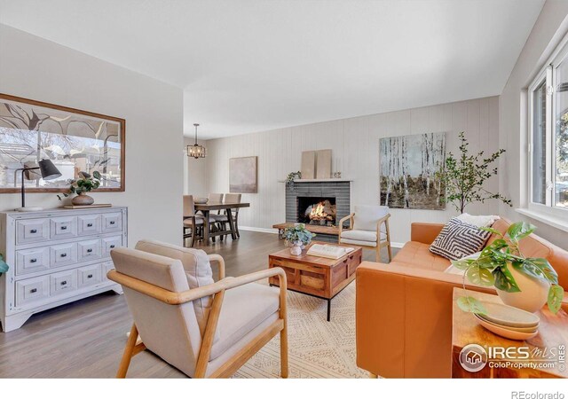 living area with a fireplace, wood finished floors, and a notable chandelier