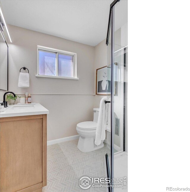 full bath with toilet, a stall shower, baseboards, and vanity