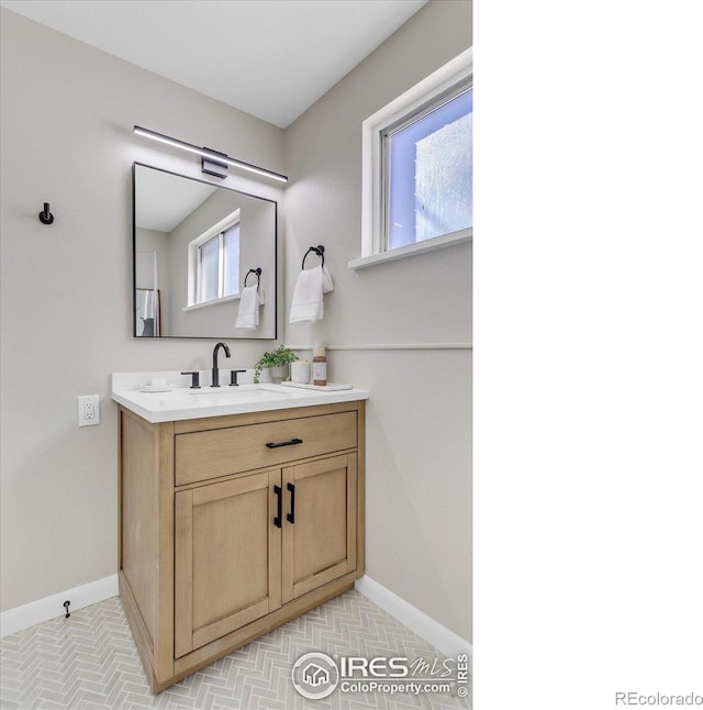 bathroom featuring a healthy amount of sunlight, baseboards, and vanity