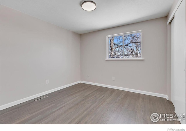 empty room with baseboards, visible vents, and wood finished floors