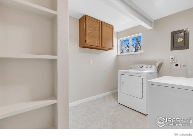 washroom with baseboards, cabinet space, electric panel, and washer and dryer