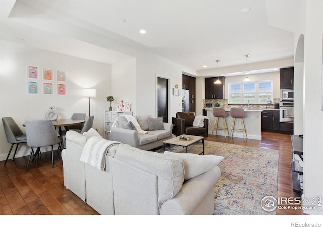 living room featuring recessed lighting, dark wood finished floors, and arched walkways