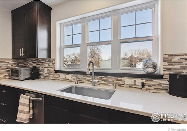 kitchen featuring a toaster, backsplash, a sink, and a healthy amount of sunlight