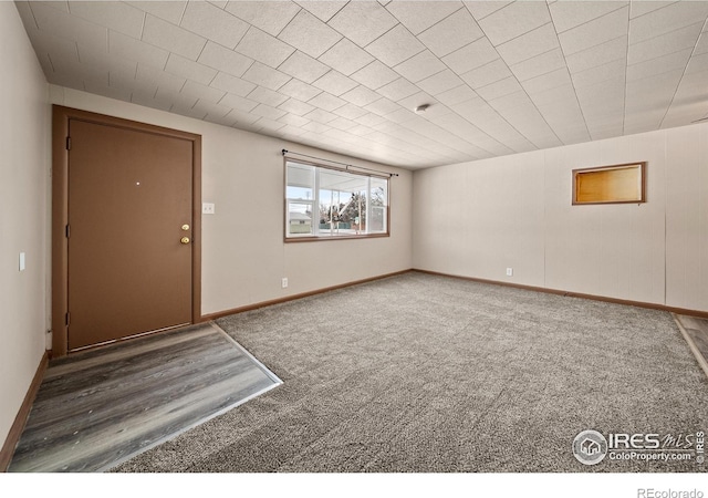 empty room featuring baseboards and dark colored carpet