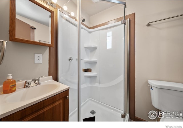 bathroom featuring vanity, a shower stall, and toilet