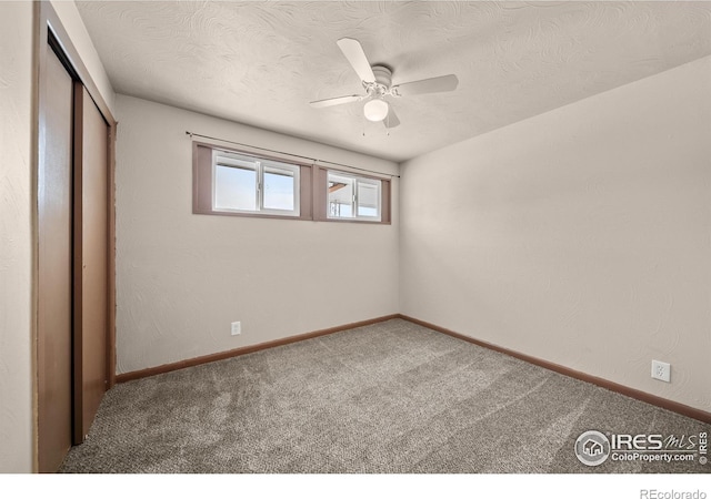 unfurnished bedroom with a closet, a ceiling fan, carpet flooring, a textured ceiling, and baseboards