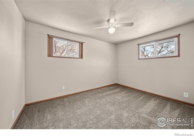 spare room with carpet floors, a textured ceiling, and baseboards