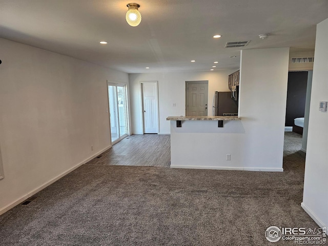 unfurnished living room featuring dark colored carpet, visible vents, baseboards, and recessed lighting