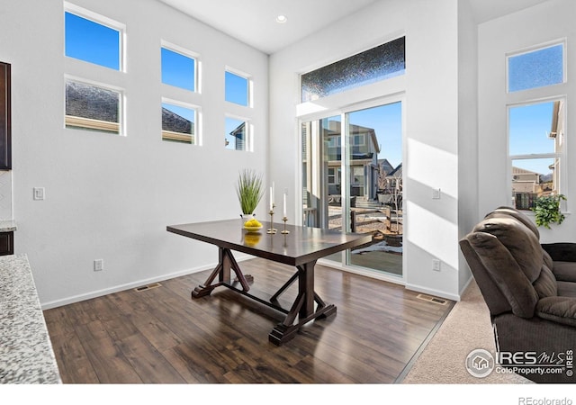 home office with dark wood-type flooring, plenty of natural light, and baseboards