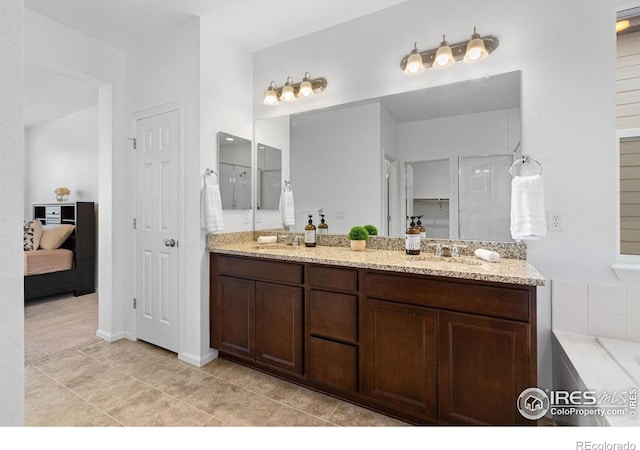 full bath featuring ensuite bathroom, double vanity, tile patterned flooring, and a sink