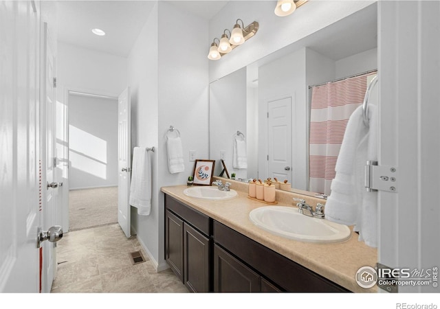 bathroom featuring visible vents, a sink, and double vanity