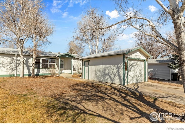 view of front facade with a garage, concrete driveway, and an outdoor structure