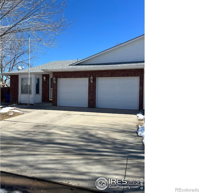 view of front of house with driveway, brick siding, and an attached garage