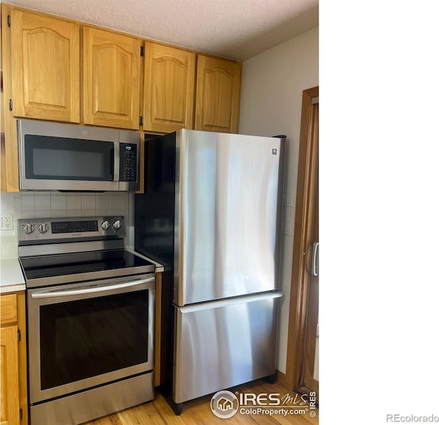 kitchen featuring stainless steel appliances, light countertops, a textured ceiling, and tasteful backsplash