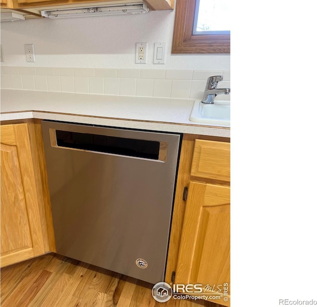 kitchen with a sink, light wood-style floors, light countertops, and dishwasher