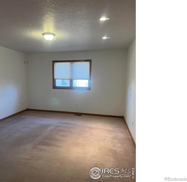 empty room with light carpet, a textured ceiling, recessed lighting, and baseboards