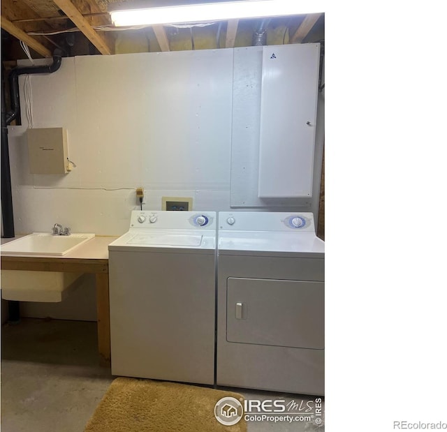 laundry area featuring washing machine and dryer, laundry area, electric panel, and a sink