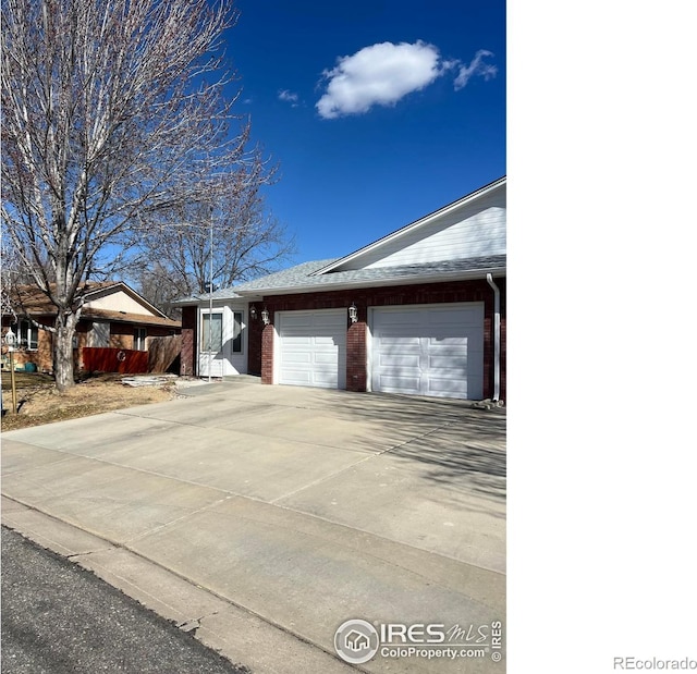 view of side of property with concrete driveway, a garage, fence, and brick siding