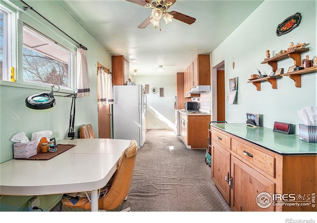 kitchen featuring carpet floors, tasteful backsplash, freestanding refrigerator, ceiling fan, and under cabinet range hood