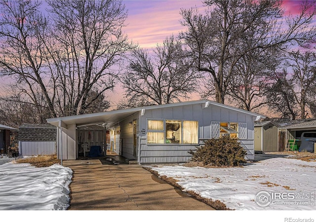 view of front of house with an outbuilding, board and batten siding, a shed, a carport, and driveway