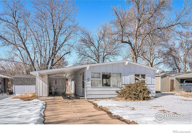 view of front facade featuring driveway, a shed, board and batten siding, and an outdoor structure