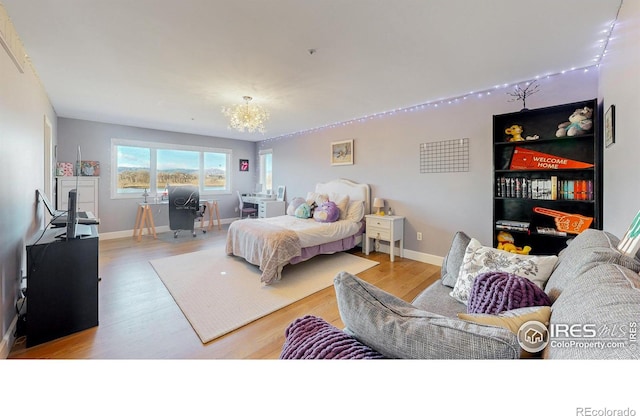 bedroom with a notable chandelier, baseboards, and wood finished floors